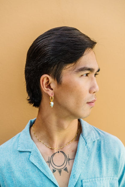 Male model wearing the Fireball Pearl Charm, featuring a blazing comet-shaped South Sea pearl on a gold hoop earring. This charm is unisex and interchangeable with other charms. This listing is for the charm only, designed to pair with 'MATAHARI' hoops or be worn as a pendant.