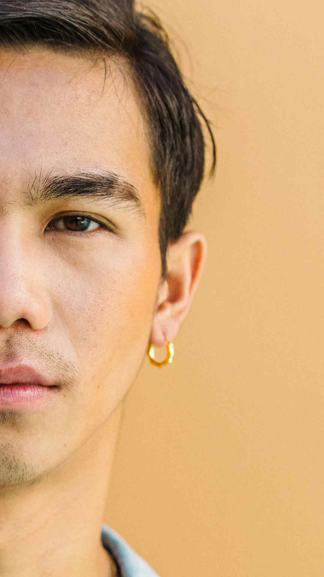 Close up of half man's face with gold hoop earrings.