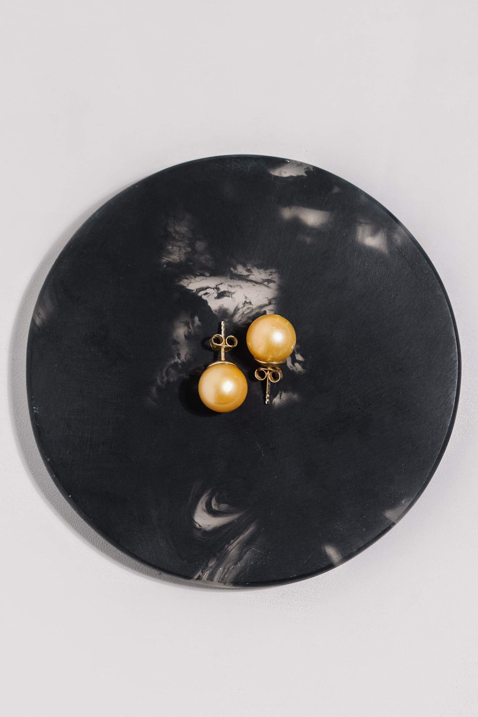 Birds eye view of large Golden yellow honey colored South Sea Pearl stud earrings set in 14k gold vermeil on black round display